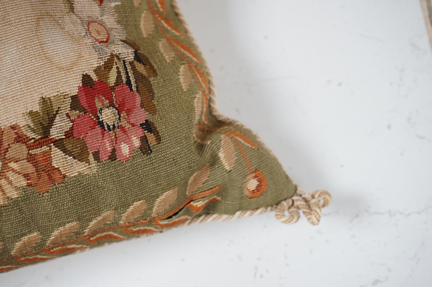 A large pair of 20th century Aubusson floral tapestry cushions. Woven with a central cartouche of roses and garden flowers within a floral border, green band of stylistic leaf design. Finished with cording and backed wit